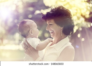 Grandmother with small baby smiling in the outdoors
