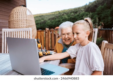 Grandmother supporting granddaughter in robotics, science, IT technologies and programming. Young girl showing her science project on laptop. - Powered by Shutterstock