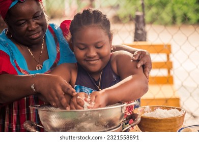 The grandmother takes her granddaughter's hands to instruct her in the preparation of the traditional foods of her culture. - Powered by Shutterstock