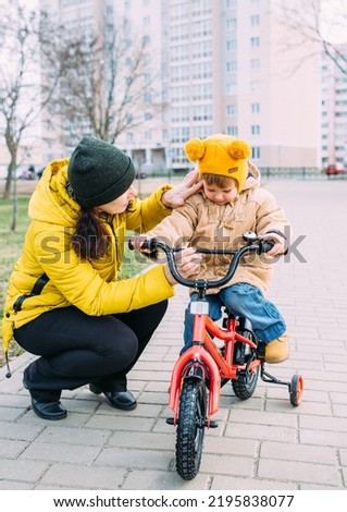 Grandmother teaches small child to ride bike for the first time in city spring