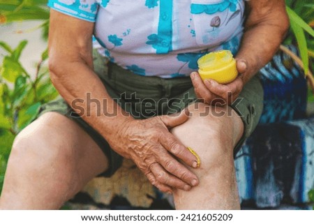 Grandmother treats her knee with home remedies. Selective focus. Nature.