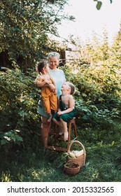 Grandmother with two grandchildren standing in garden and looking each other happy family.