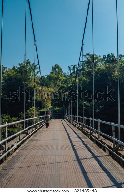 a grandmother walked on the Suspension Bridge,\
Kali Boyong Yogyakarta