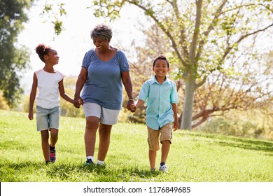 Grandmother Walking In Park And Holding Hands With Grandchildren