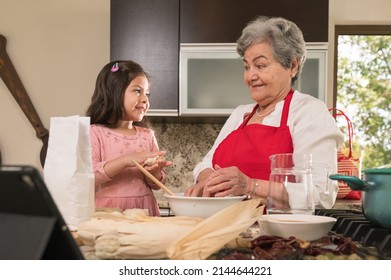 Grandmother Watching Her Granddaughter During A Traditional Hispanic American Cooking Lesson.