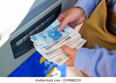 Grandmother Withdraws Her Pension At An ATM. A Woman Holds Polish Money And Zloty Bills In Her Hands