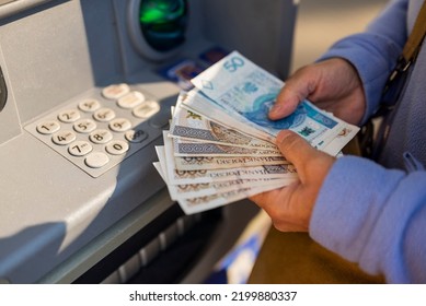 grandmother withdraws her pension at an ATM. A woman holds Polish money and zloty bills in her hands - Shutterstock ID 2199880337