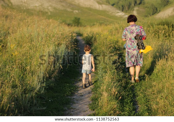 A grandmother with young grandchild went for a walk,\
a grandmother carries a car on a rope, a family walks in nature, a\
happy family and a young grandmother stroll in the village. People\
on a walk bac