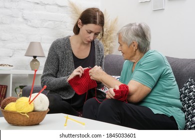 Grandomther And Granddaughter Spending Quality Time Together In Creative And Fun Ways Whilst Strengthening Their Family Bonds. Senior Woman Teaching Young Woman How To Knit. Craft And DIY Concept.