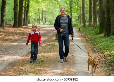 Grandpa And Grandchild Are Walking The Dog In The Forest