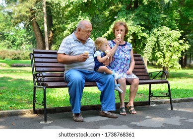 Grandpa, grandma and and granddaughter eat ice cream on the bench
