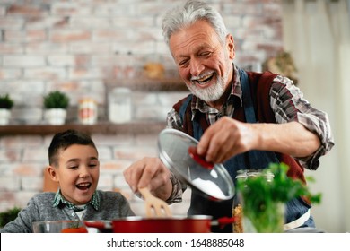Grandpa And Grandson Playing. Old Man Cooking In Kitchen With Grandson. 
