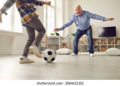 Grandpa And Grandson Playing Soccer At Home. Child And Grandfather Spending Time Together. Little Kid And His Grandad Having Fun. Senior Man Playing As Goalkeeper While Playing Football With Grandkid