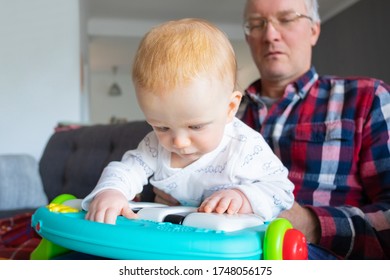 Grandpa Holding Baby Granddaughter Playing Toy Piano. Closeup Shot. Family Or Learning Games Concept