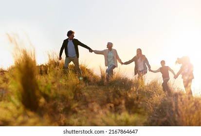 Grandpa is in the lead. Shot of a multi-generational family walking hand in hand across a field at sunset. - Powered by Shutterstock