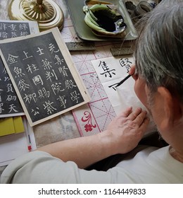 Grandpa Is Practicing Chinese Calligraphy With Black Ink (translation Of The Characters: Yin, Yang, Union, Gold, Study, Peace, Life)