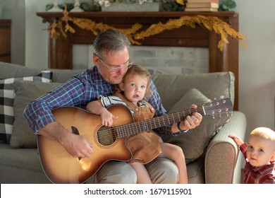 Grandpa Spending A Special Moment With Two Young Grandkids, Singing And Playing Guitar