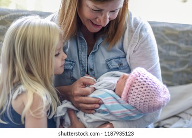 Grandparent And Little Girl Holding Newborn Baby Girl