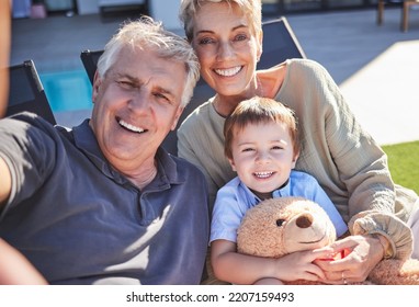 Grandparents, Boy And Backyard Selfie In Home On Lawn Chairs On Grass Sharing Love, Energy And Bonding. Portrait Of Retired Happy Man, Woman And Kid With Teddy, Caring And Enjoying Time Together.