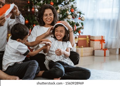 Grandparents And Children Having Fun During Christmas Day Celebration At Home With Family