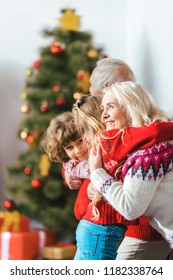 Grandparents Embracing With Kids On Christmas At Home