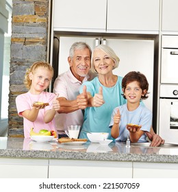 Grandparents and grandchildren holding thumbs up during breakfast in kitchen
