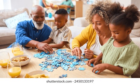 Grandparents With Grandchildren Indoors At Home Doing Jigsaw Puzzle With Parents In Background - Powered by Shutterstock
