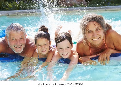 Grandparents With Grandchildren On Airbed In Swimming Pool