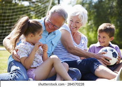 Grandparents And Grandchildren Playing Football In Garden