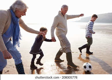 Grandparents With Grandchildren Playing Football On Beach