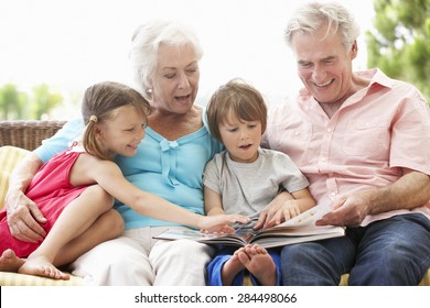 Grandparents And Grandchildren Reading Book On Garden Seat - Powered by Shutterstock