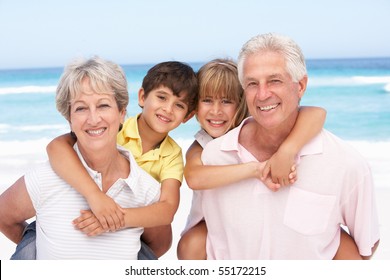 Grandparents And Grandchildren Relaxing On Beach Holiday