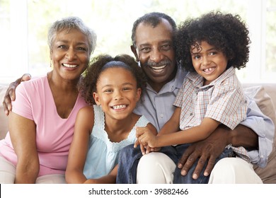 Grandparents With Grandchildren Relaxing On Sofa At Home Together