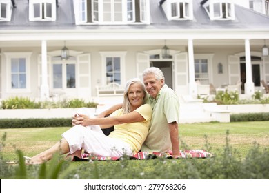 Grandparents And Grandchildren Sitting Outside House On Lawn