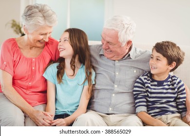Grandparents and grandchildren sitting together on sofa in living room