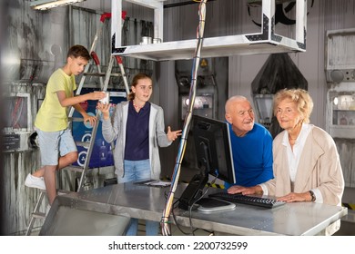 Grandparents and grandchildren solving conundrums in escape room. They're using computer and stepladder.