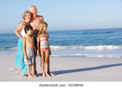 Grandparents And Grandchildren Standing On Sandy Beach