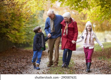Grandparents With Grandchildren Walking Along Autumn Path
