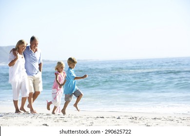 Grandparents And Grandchildren Walking Along Beach