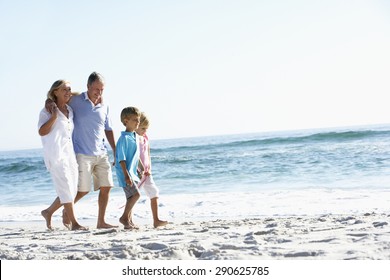 Grandparents And Grandchildren Walking Along Beach