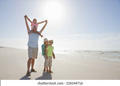 Grandparents And Grandchildren Walking On Sunny Beach