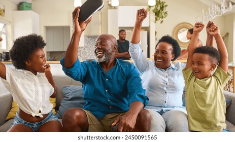 Grandparents With Grandchildren Wearing Virtual Reality Headset Playing Game At Home Together - Powered by Shutterstock