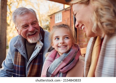 Grandparents With Granddaughter Outside House Getting Ready To Go For Winter Walk