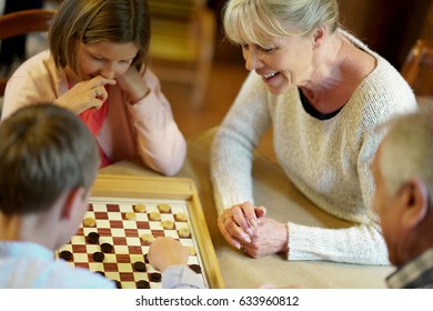 Grand-parents With Grandkids Playing Checkers