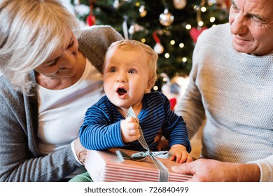 Grandparents With Grandson At Christmas Tree At Home.