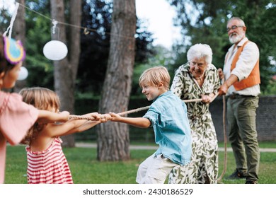 Grandparents have a tug of war with their grandkids. Fun games at family garden party. - Powered by Shutterstock