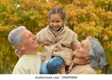 Grandparents with her granddaughter in the autumn park