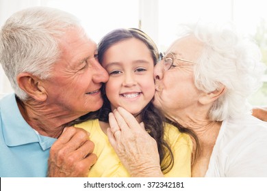 Grandparents kissing their granddaughter at home