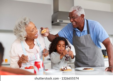 Grandparents In Kitchen With Granddaughter Making Pancakes Together - Powered by Shutterstock