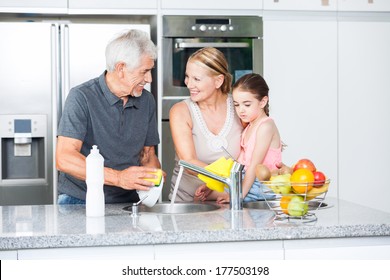 Grandparents and little girl washing dishes, grandfather grandmother and grandchild happy smile on modern kitchen - Powered by Shutterstock